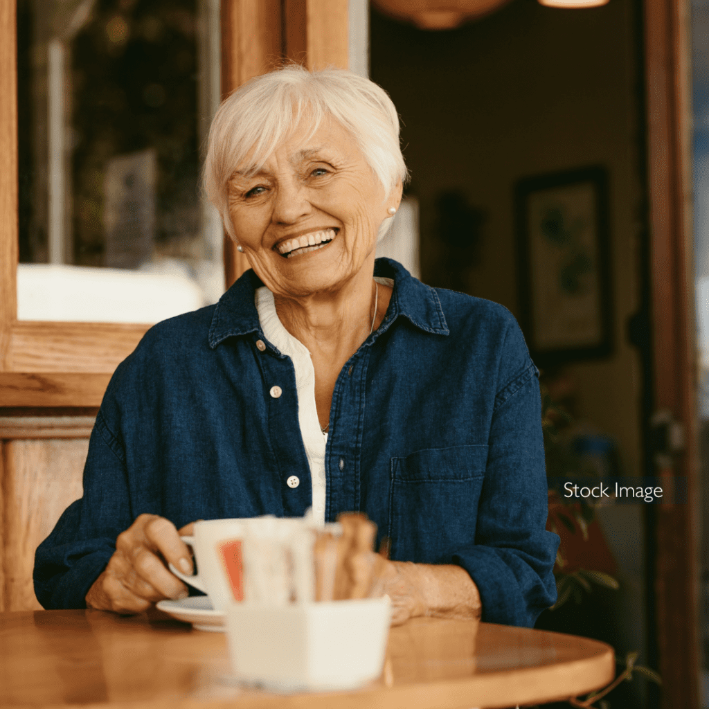 Smiling elderly lady drinking coffee in a cafe after cataract surgery stock image