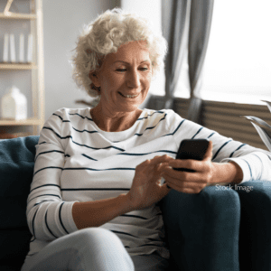 Older lady looking at phone smiling on the sofa