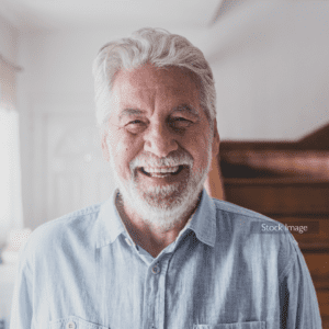 Older man smiling in his pale blue shirt after eye surgery