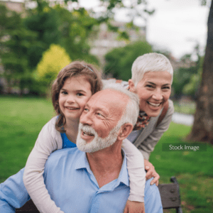 Elderly man and his grandchild and lady outside playing and smiling