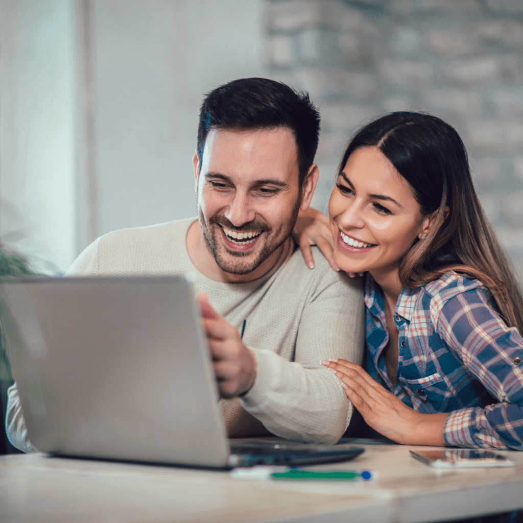 Young couple looking at laptop smiling doing research